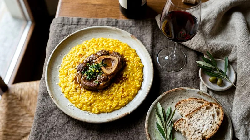 Saffron risotto alla milanese with ossobuco and red wine on a linen tablecloth.